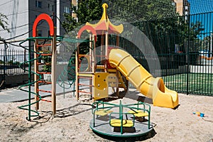 New children`s playground with a yellow slide and a swing in the summer on a sunny day