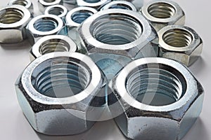 New chrome screw-nut of different sizes on a white background.