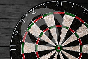 New classic professional sisal dart board on black wooden background. Close up.