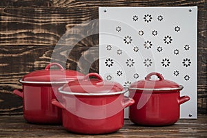 New And Clean Covered Red Saucepans on Brown Wooden Background