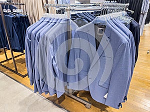 New collection modern men's suits are hanging on hangers in the clossing store