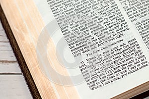 New commandment verse in open holy bible book with golden pages, close-up