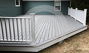 New composite deck on the back of a house with green vinyl siding