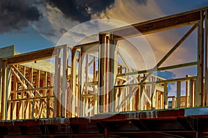 New construction home residential construction home framing against a dramatic sunset sky bright horizon