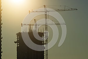 New construction site of developing residense in american urban area at sunset. Industrial tower lifting cranes in Miami