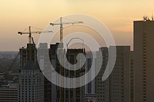 New construction site of developing residense in american urban area at sunset. Industrial tower lifting cranes in Miami