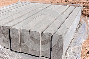 a new curbstone or curb unpacked stands in a pallet in several rows