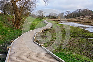 New curved wooden footpath for walk in nature park photo