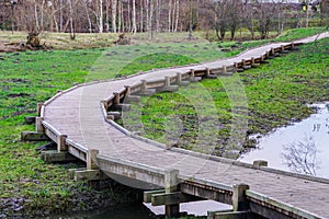 New curved wooden footpath for walk in nature park photo