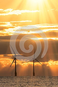 New dawn. Offshore wind turbines silhouetted by beautiful sunrise