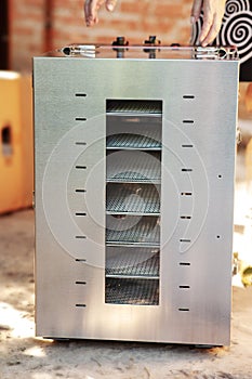 New dehydrating machine standing on the ground, woman hands unpacking it. Equipment for producing dry meat or vegetarian jerky.