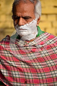 New Delhi, India - March 04, 2020: Handsome old man shaving his beard in bathroom during morning time at Yamuna river ghat in New