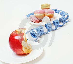 New diet concept, question sign in shape of measurment tape between red apple and donut isolated on white