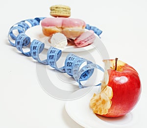 New diet concept, question sign in shape of measurment tape between red apple and donut isolated on white close up