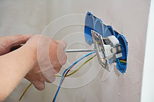 New electrical socket installation. An electrician is attaching a new power outlet with power wires to the electrical box,