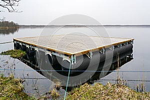 A new empty wooden platform on pontoons in the lake for the creation of a holiday house on the water