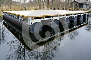 A new empty wooden platform on pontoons in the lake for the creation of a holiday house on the water