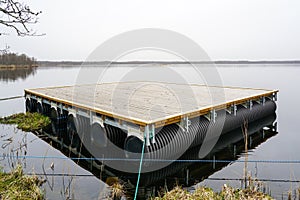 A new empty wooden platform on pontoons in the lake for the creation of a holiday house on the water