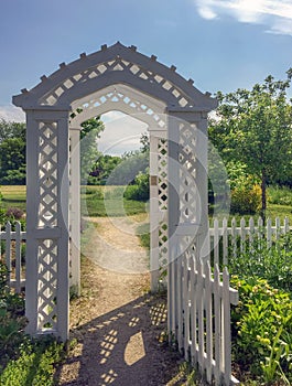 New England white wooden arbor garden gates and sunlit path