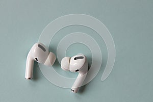 New fashionable white wireless bluetooth headphones on a gray-blue background, close-up, macro, top view. The concept of the use