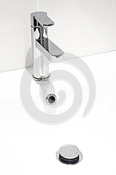 A new faucet on the washstand in a bathroom with white walls. Repair