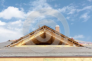 New frame house under construction. Roof with asphalt shingles, chimney and insulation material.