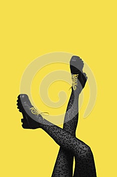 New gray female boots on long slender crossed woman legs in gray tights isolated on yellow background