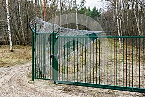 A new green metal mesh fence with coiled barbed wire and gate around the restricted area