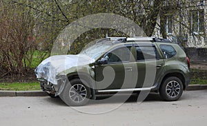 A new green wrecked car after an accident is covered with plastic wrap