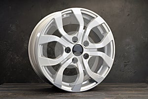 new grey alloy wheels on a dark textured black background. a wheel for a car