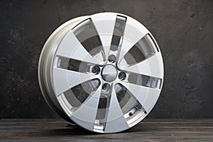 new grey alloy wheels on a dark textured black background. a wheel for a car