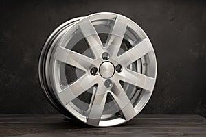 new grey alloy wheels on a dark textured black background. a wheel for a car
