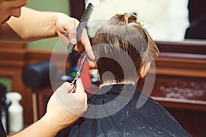 New hairstyle for young boy. Barber shop. Child getting haircut by hairdresser at the barbershop