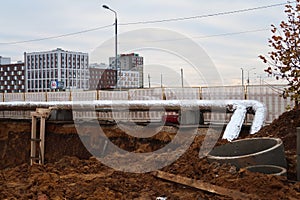 New heating main pipe laying, shiny thermal insulation, loose soil and old concrete structures