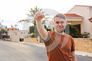 New home, apartment, owner and people concept - Close up of keys that showing young happy man with new home on