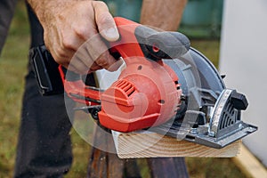 Building contractor worker using hand circular saw to cut boards on a new home constructiion project