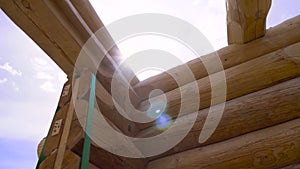 New home construction framing on sunny sky background. Clip. Bottom view of new logs and unfinished wooden house at the