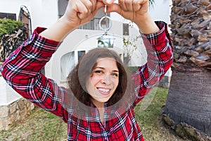 New home, house, property and tenant - Young funny woman holding key in front of her new home after buying real estate