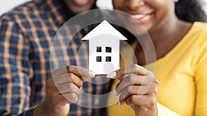 New Home Owners. Happy african american spouses holding paper house figure