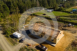 New home under construction in rural area with pine trees around it