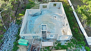 New home under construction. Unfinished frame of private house with brick concrete walls ready for mounting wooden roof