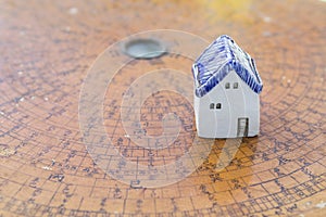 Ceramic miniature house on ancient wooden feng shui compass background