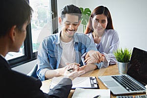 New house / home moving and relocation concept. Happy asian couple receiving apartment key from real estate agent / realtor