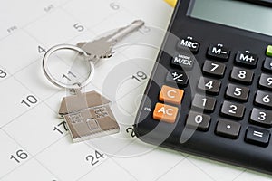 New house purchase, mortgage schedule reminder or real estate payment day, silver house keyring with calculator on white clean