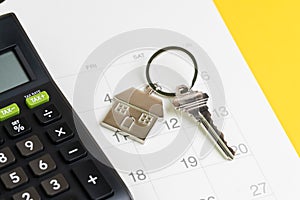 New house purchase, mortgage schedule reminder or real estate payment day, silver house keyring with calculator on white clean