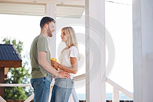 New house with terrace, couple standing and drink coffee with plaid relaxing enjoying beautiful view