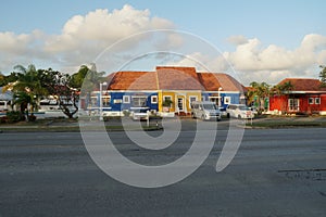 New house in typical bright colors and colonial style surrounded by palm trees on the Caribbean island of Barbados.