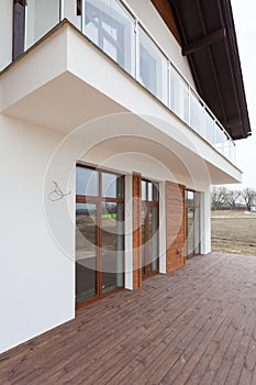 New house with white walls, wooden terrace and glass balcon. photo