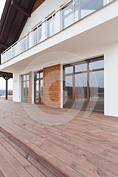 New house with white walls, wooden terrace and glass balcon. photo