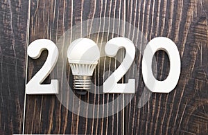 New idea 2020. Light bulb and numbers on a wooden background